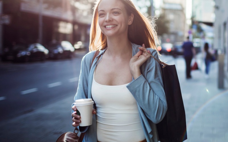 image of a woman walking through a city with a coffee in her hand